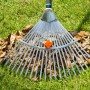Rastrello per foglie su prato con foglie autunnali. Ideale per il giardinaggio.
