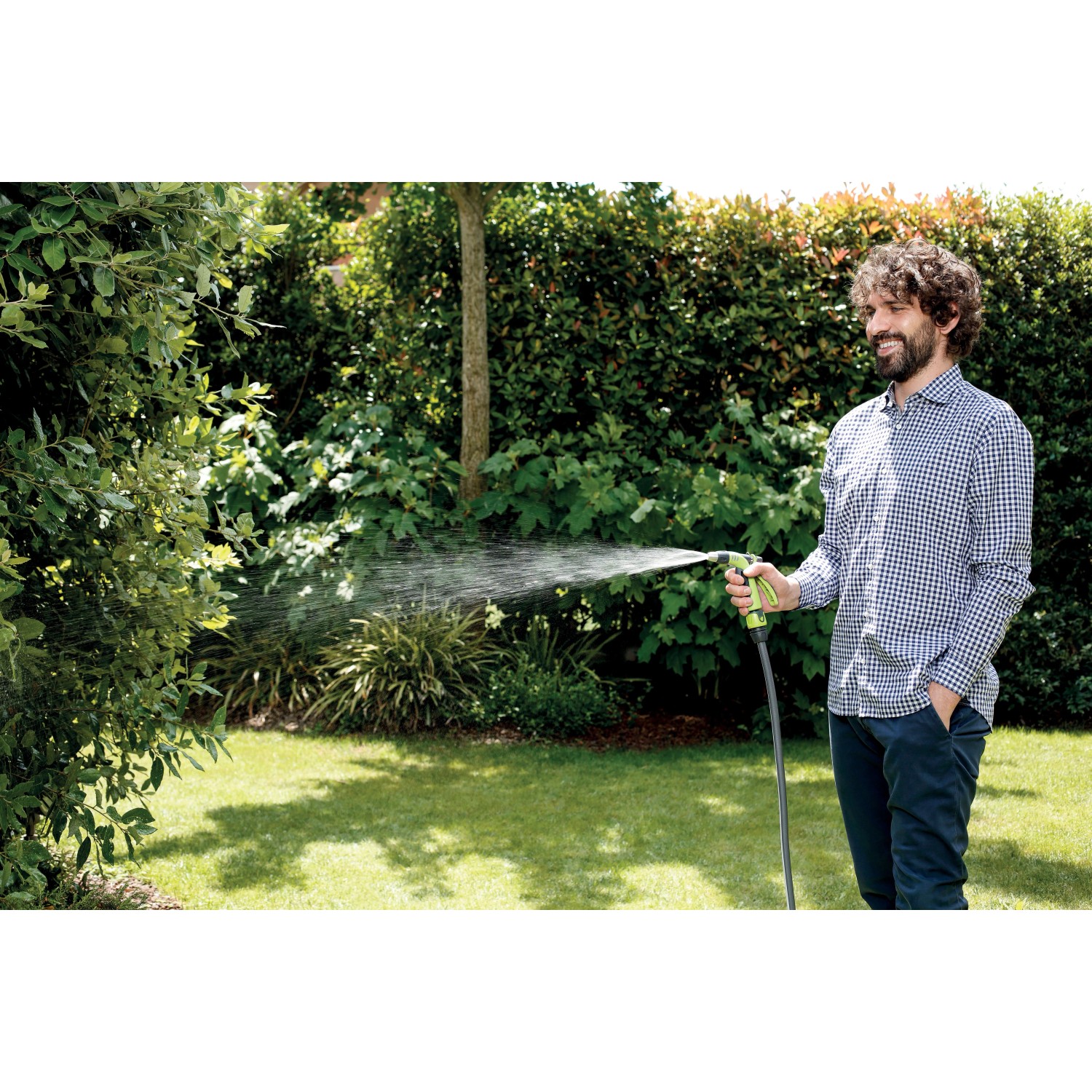 Uomo che irriga il giardino con lancia/pistola per irrigazione t.b.t.
