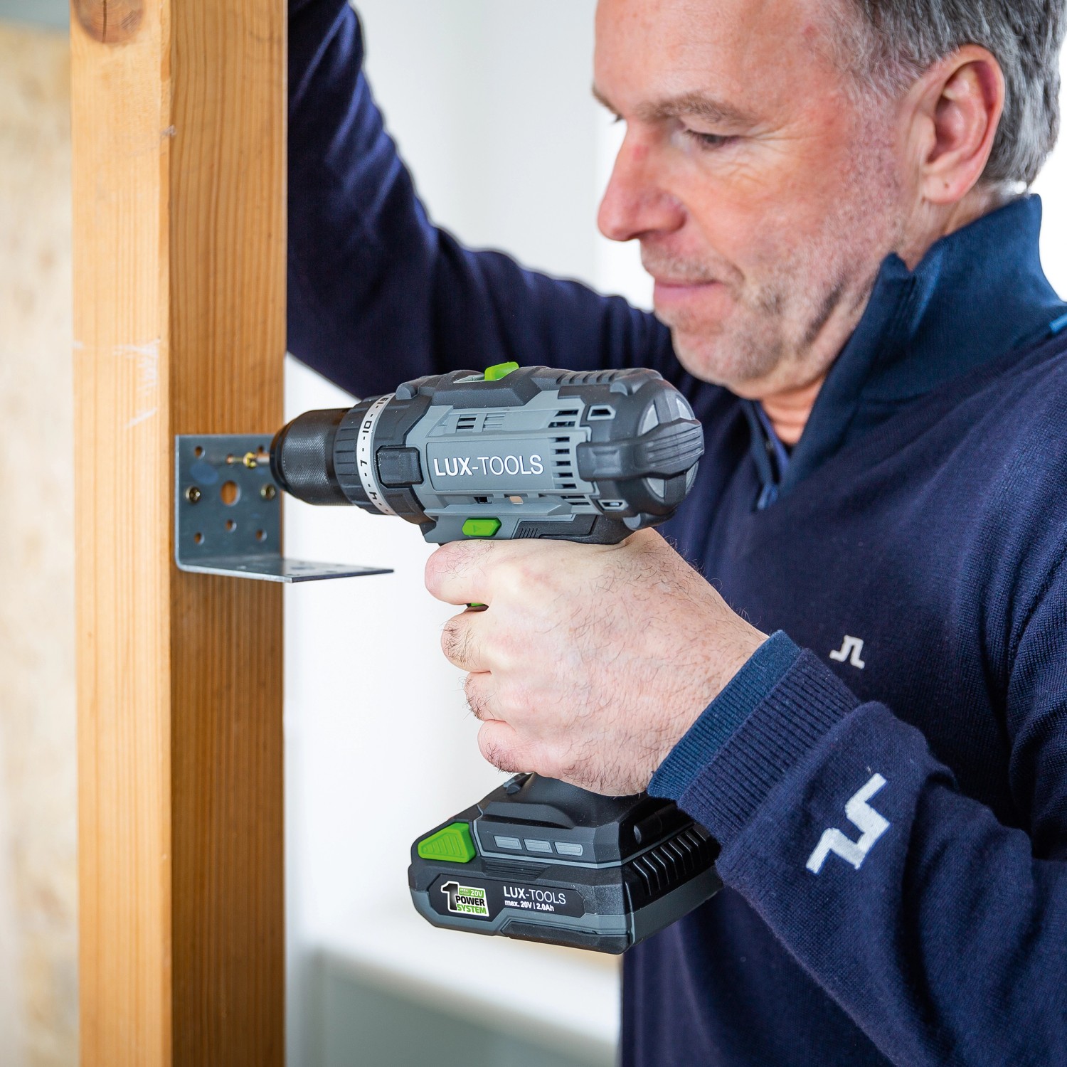 Uomo che fora una staffa angolare su un telaio di legno con avvitatore a batteria LUX A-BS-20.