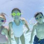Tre bambini con occhialini da nuoto colorati sott'acqua in piscina. Maschere, occhialini e accessori da immersione.