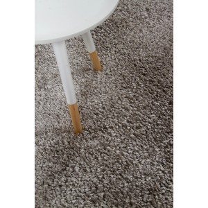 Dettaglio di un tappeto a pelo lungo grigio accanto a un tavolino.