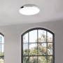 Plafoniera LED bianca Brilo Malbona (Ø 35,5 cm) con bordo cromato sul soffitto della stanza.