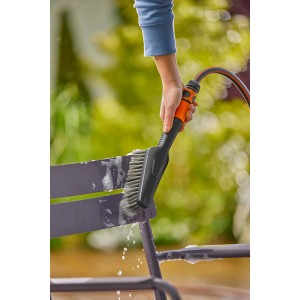 Gardena Cleansystem Spazzola a mano Soft S con raccordo per tubo flessibile in uso per pulire una sedia da giardino.