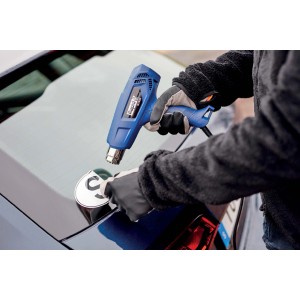 Pistola termica blu che rimuove un adesivo dal finestrino di un'auto.