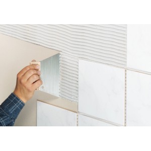 Spatola dentata LUX Classic 6x6 mm che applica adesivo per piastrelle su una parete.