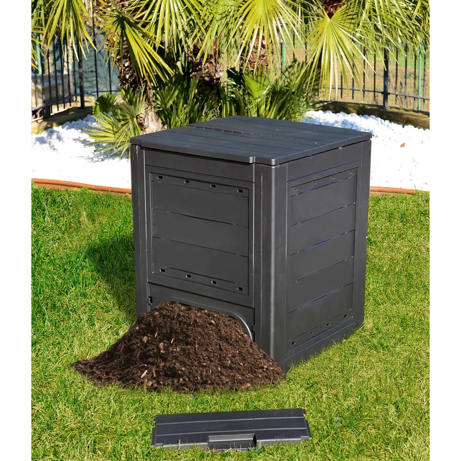 Compostiera t.b.t. nera con mucchio di compost nel giardino.