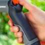 Mano che tiene la pistola a spruzzo Gardena Classic, spruzzatore da giardino con grilletto arancione.
