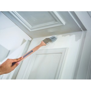 Pennello angolare LUX 60 mm mentre vernicia una porta. Ideale per aree difficili da raggiungere.