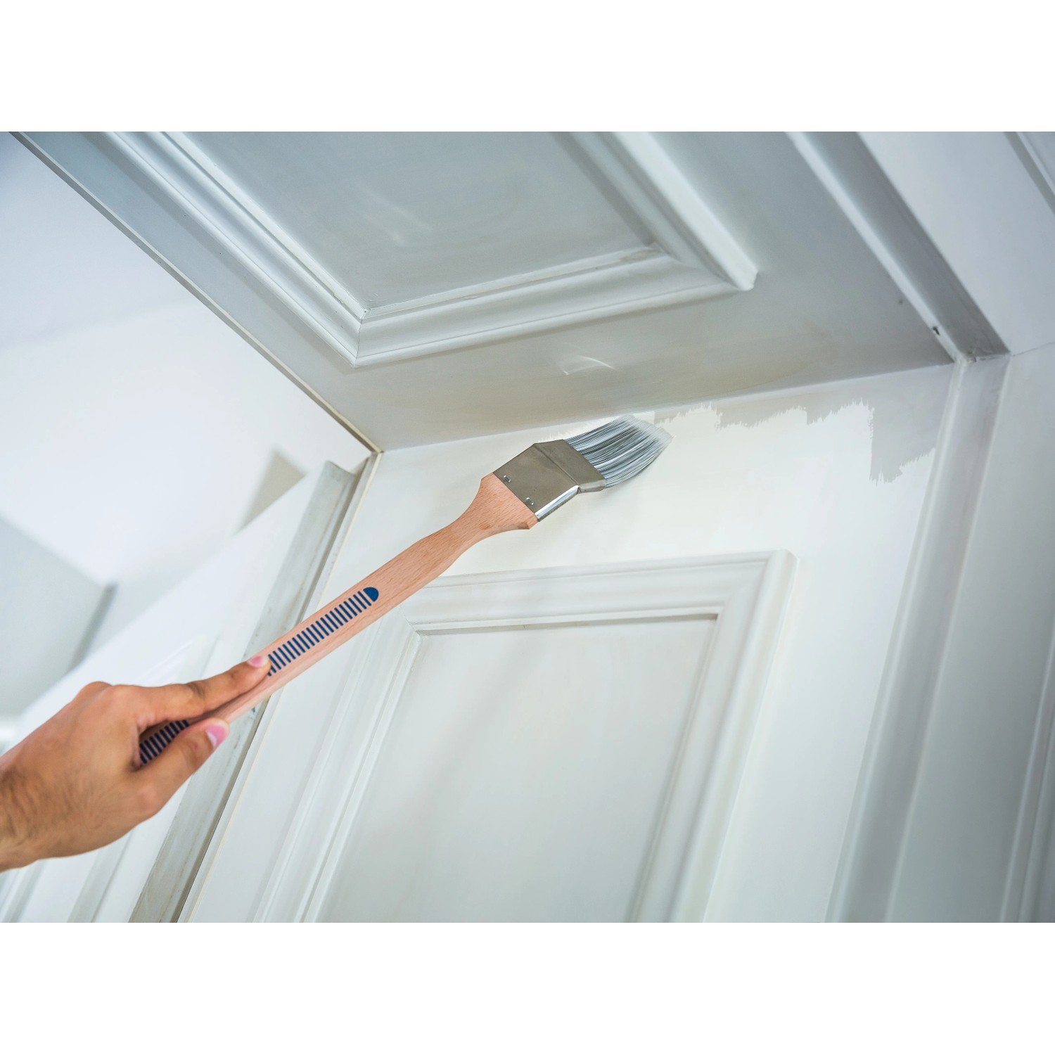 Pennello angolare LUX 60 mm mentre vernicia una porta. Ideale per aree difficili da raggiungere.