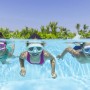 Bambini con maschere da sub colorate in piscina. Divertimento in acqua con occhialini e accessori.