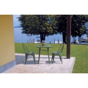 Tavolo da giardino verde con due sedie su un patio con vista lago.