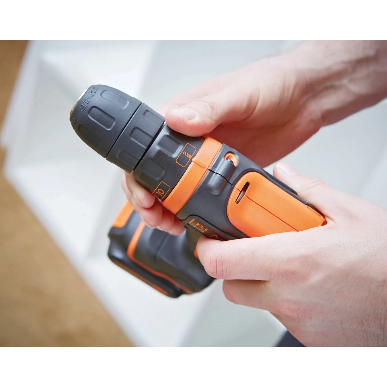 Avvitatore a batteria Black+Decker BDCDD12K in mani, arancione e nero.