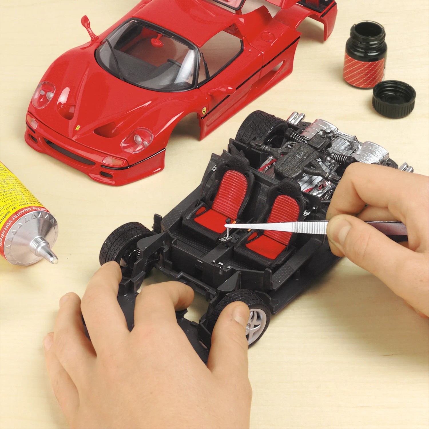 Set di meccanica di precisione: Modellismo di un'auto sportiva rossa con pinzette e colla.