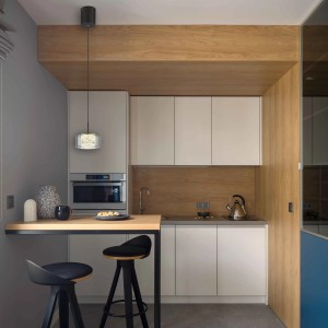 Cucina moderna con lampada a sospensione t.b.t. sopra un bancone con sgabelli.