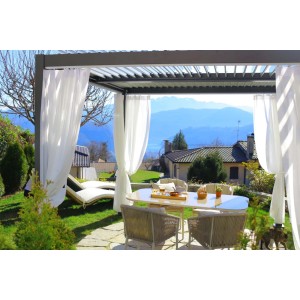 Patio con pergola e tende bianche, tavolo e sedie. Accessorio per la protezione solare.