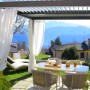 Patio con pergola e tende bianche, tavolo e sedie. Accessorio per la protezione solare.