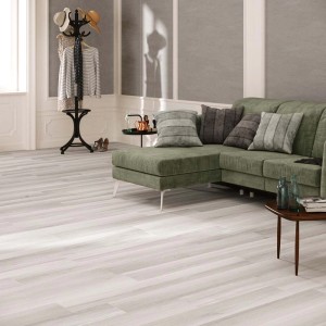Stanza luminosa con piastrelle per pavimenti effetto legno. Divano verde e decorazioni.