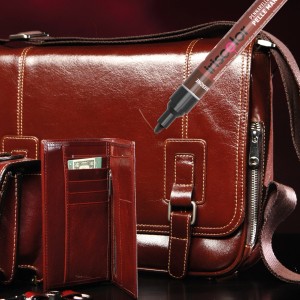 Pennarello riparatore in pelle marrone accanto a portafoglio e borsa. Smalti colorati.