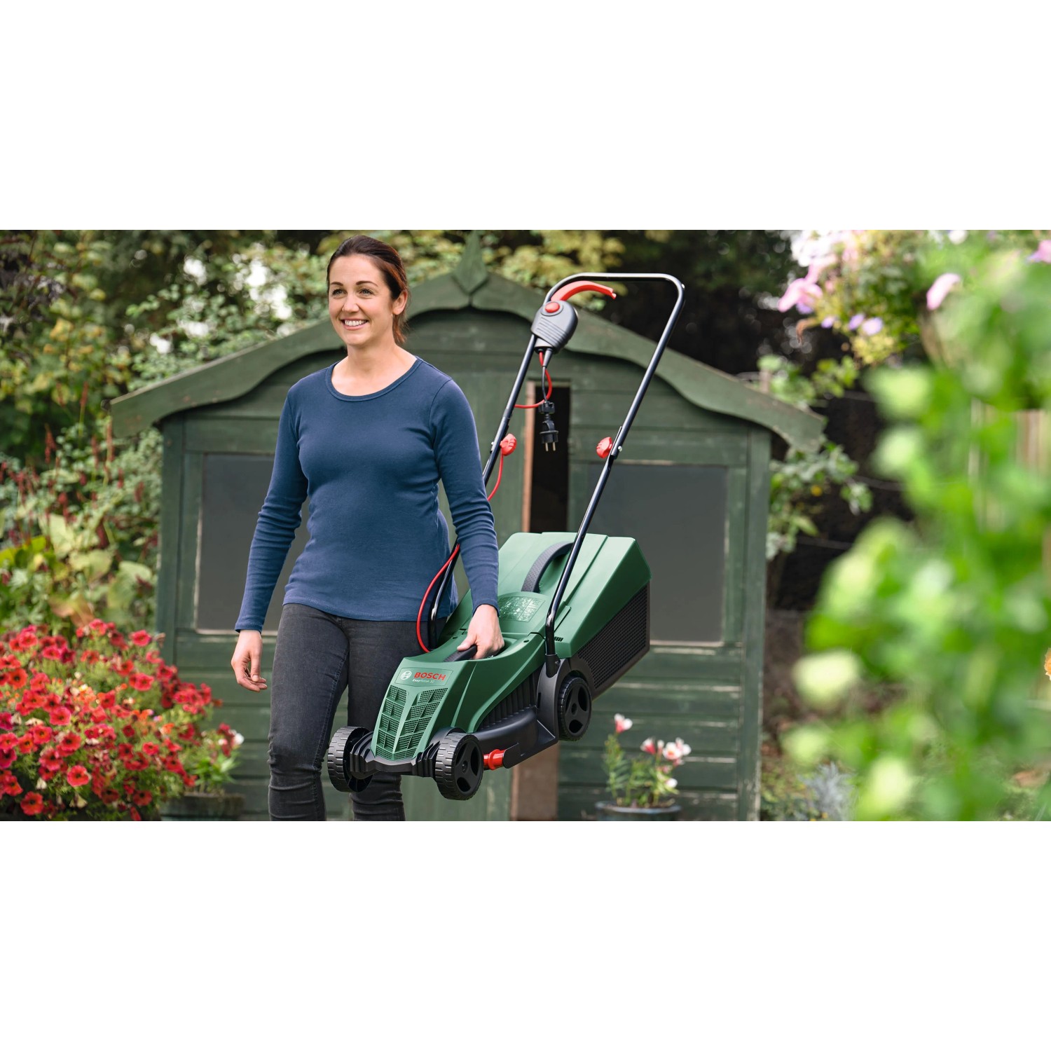 Donna trasporta tosaerba elettrico Bosch Easy Rotak 32-215 verde in giardino. Leggero e maneggevole.