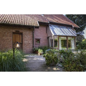 Lampada da esterno davanti a casa in mattoni con giardino d'inverno. Illuminazione decorativa da giardino.