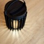 Lampada da tavolo solare a LED Lutec Kozy nera con struttura a griglia e maniglia.