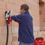 Uomo che utilizza una scanalatrice per tagliare fessure in un muro di mattoni.