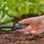 Primo piano di una mano che installa un sistema di microirrigazione t.b.t. in giardino.