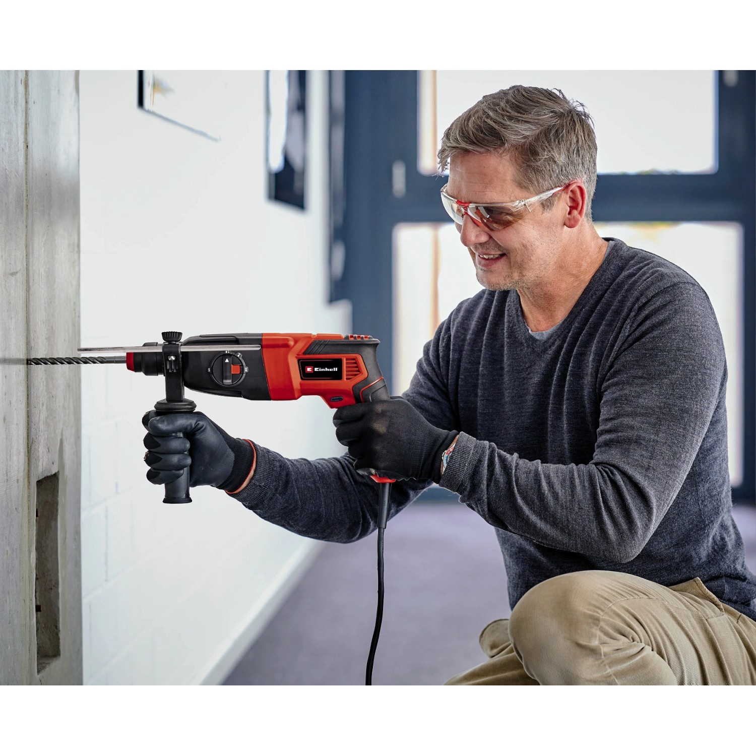 Uomo che fora un muro con il martello perforatore Einhell TC-RH 620 4F Kit.