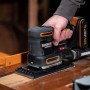 Levigatrice multifunzione a batteria Worx 20 V WX820.9 Solo mentre leviga una superficie in legno.