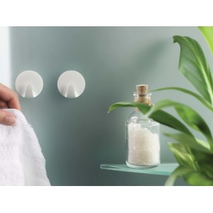 Due ganci adesivi t.b.t. bianchi e rotondi su una parete del bagno.