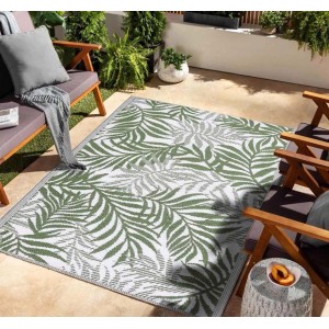 Tappeto da esterno verde con motivo a foglie su patio con mobili da giardino.