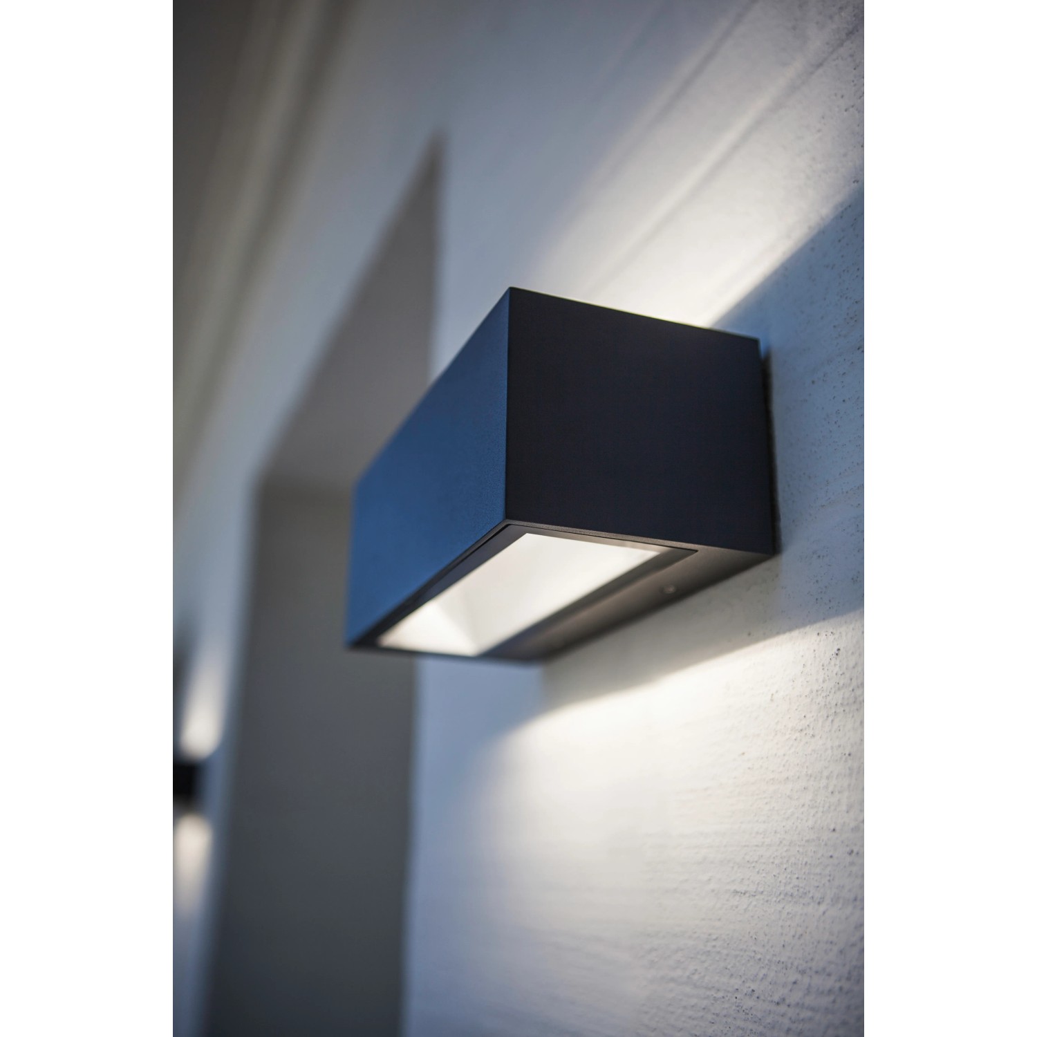 Moderna lampada da parete per esterni a LED Lutec Gemini color antracite montata su una parete.