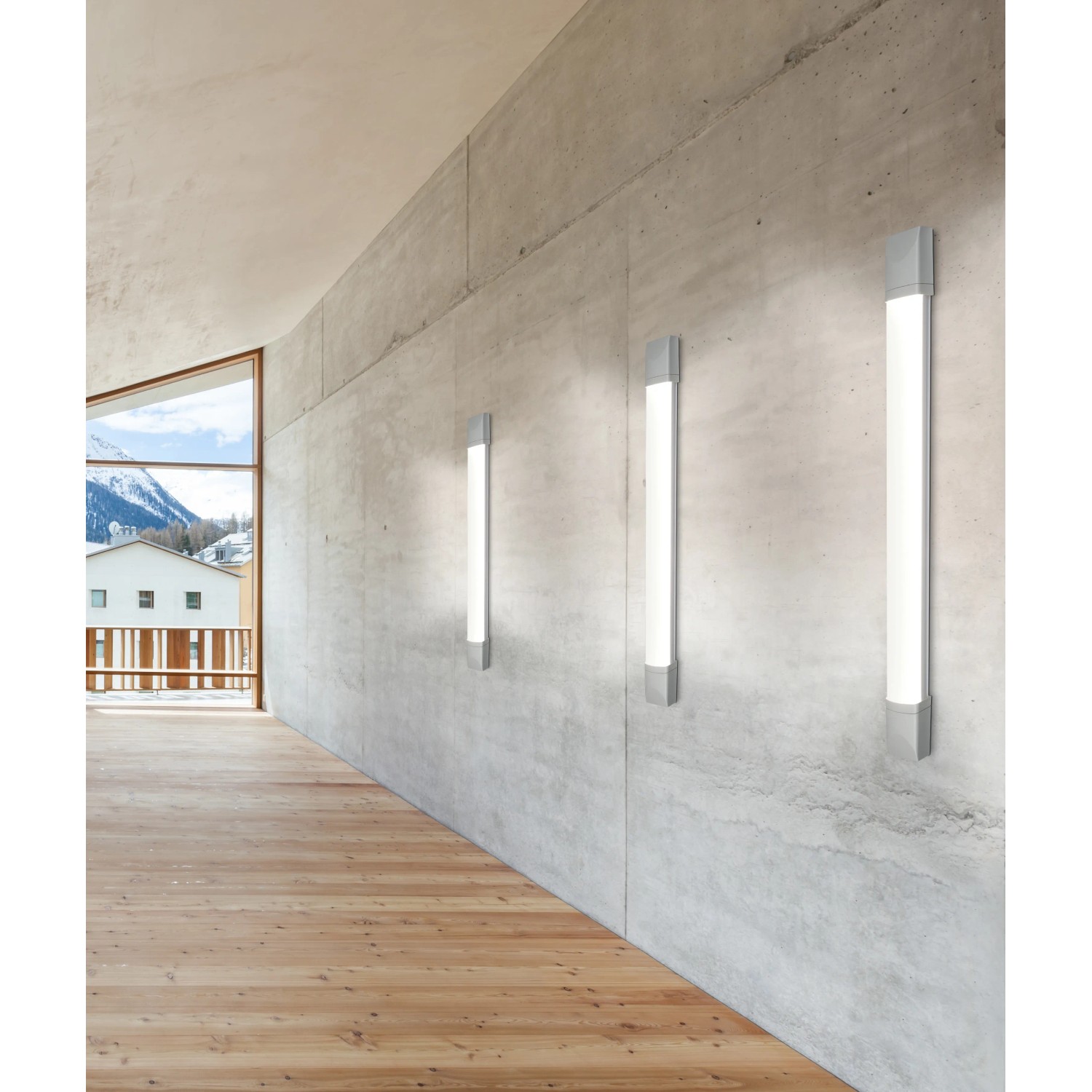 Tre luci sottopensile LED grigie t.b.t. su una parete di cemento in una stanza con pavimento in legno.