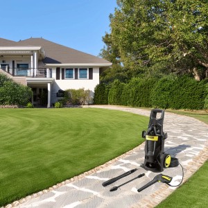 Idropulitrice con accessori su un sentiero lastricato davanti a casa e giardino.