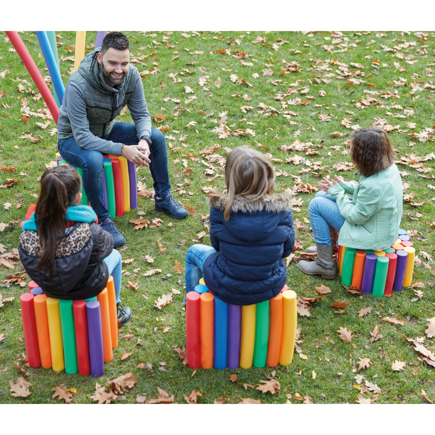 Persone sedute su sgabelli fatti di colorate Comfy noodles da piscina in giardino.