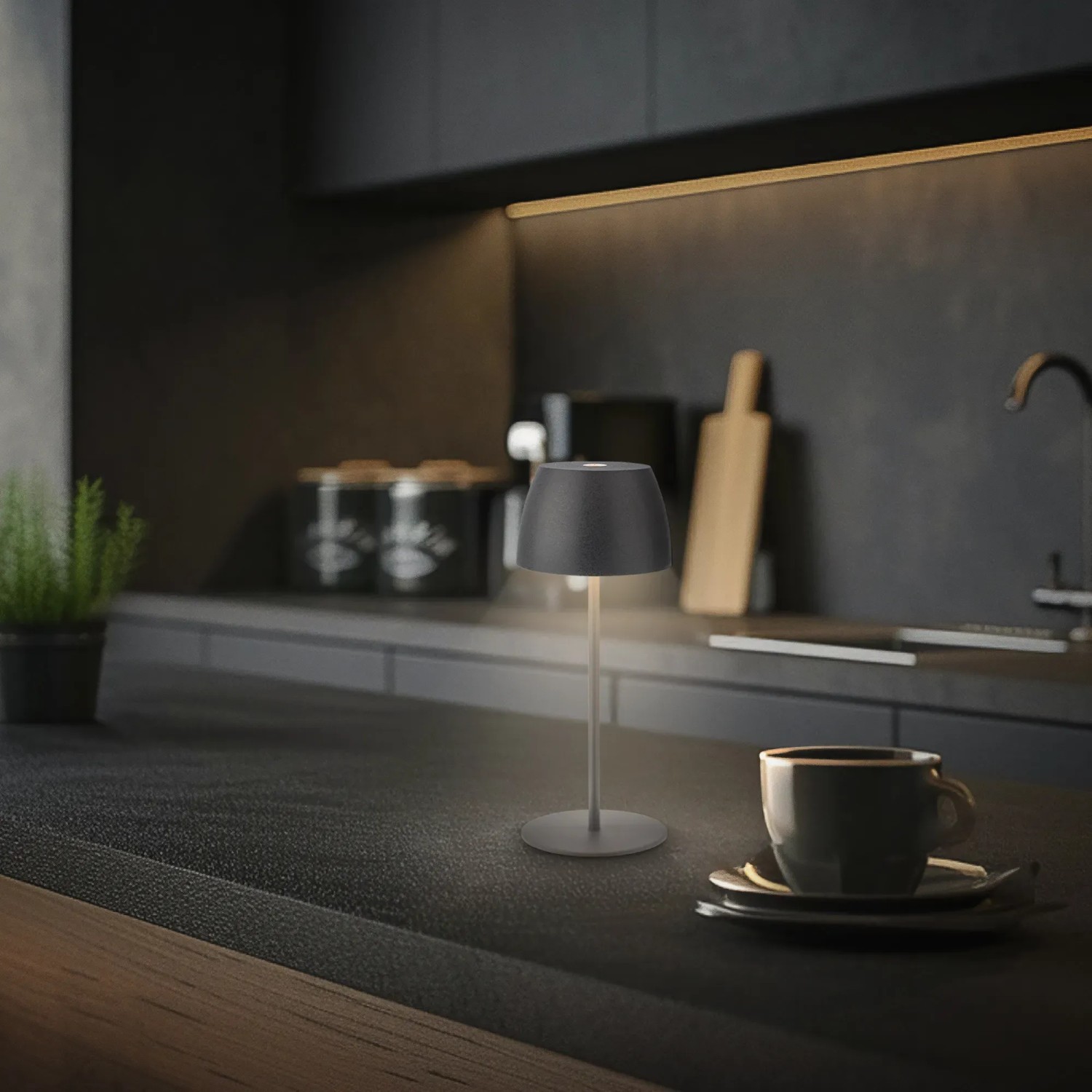 Lampada da tavolo a LED ricaricabile Brilo Serina Mini antracite (20 cm) su piano di lavoro scuro.