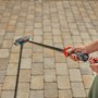 Gardena Cleansystem Spazzola a setole dure con raccordo per tubo flessibile in uso per la pulizia di pavimentazioni.