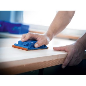 Mano che leviga il legno con il rotolo abrasivo LUX K240 e il blocco di levigatura. Abrasivo per lavori di precisione.