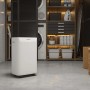 Deumidificatore bianco in una moderna lavanderia con scaffali e lavatrice.