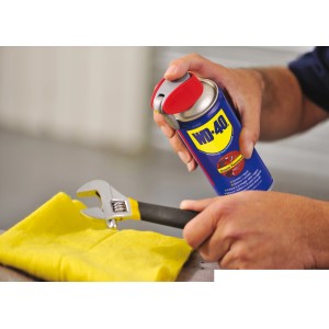 Prodotto multifunzione WD-40 spruzzato su chiave inglese. Spray universale per manutenzione e riparazione.