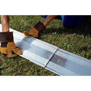 Mani con guanti che posano t.b.t. ciottoli e graniglia su prato.