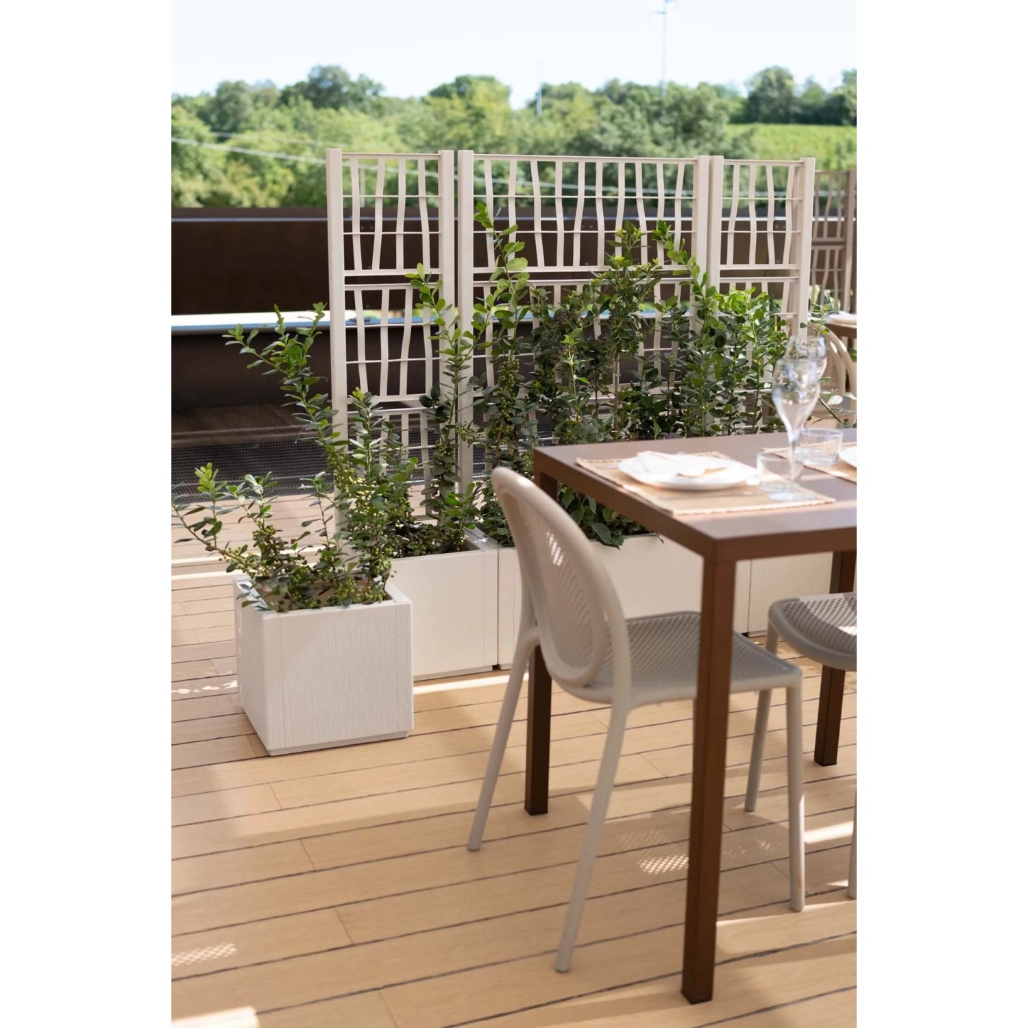 Fioriere da esterno t.b.t. quadrate bianche con piante e grigliato su una terrazza.