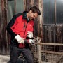 Uomo che smeriglia metallo con una smerigliatrice t.b.t. Indossa occhiali e guanti di protezione.
