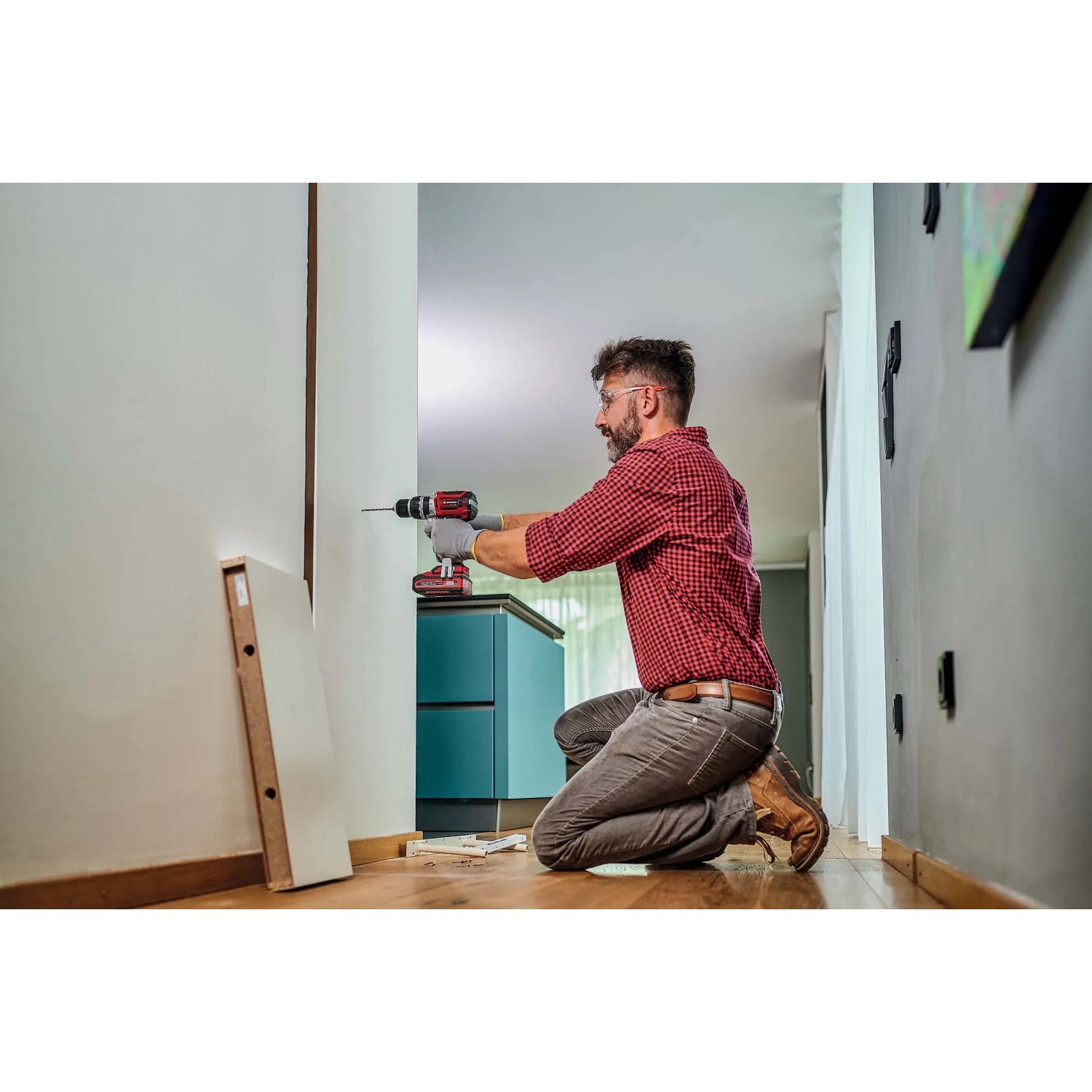 Uomo che fora un muro con il trapano avvitatore a percussione a batteria Einhell TP-CD 18/60 Li-i BL Solo.