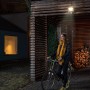 Faretto LED da esterno Ledvance Endura Flood grigio scuro con sensore illumina donna con bicicletta.
