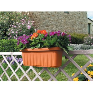 Fioriera marrone con fiori colorati, fissata a una recinzione di legno.