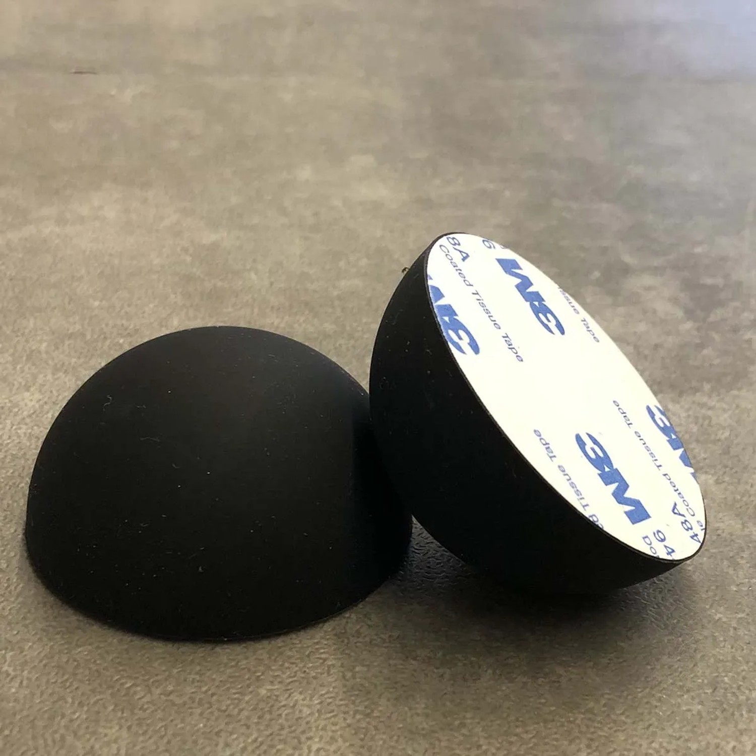 Due cuscinetti neri, emisferici con superficie adesiva per accessori lavatrice.
