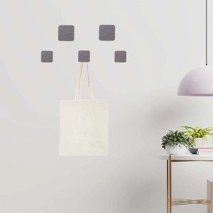 Appendiabiti da parete con cinque ganci quadrati grigi, uno con una borsa di stoffa.