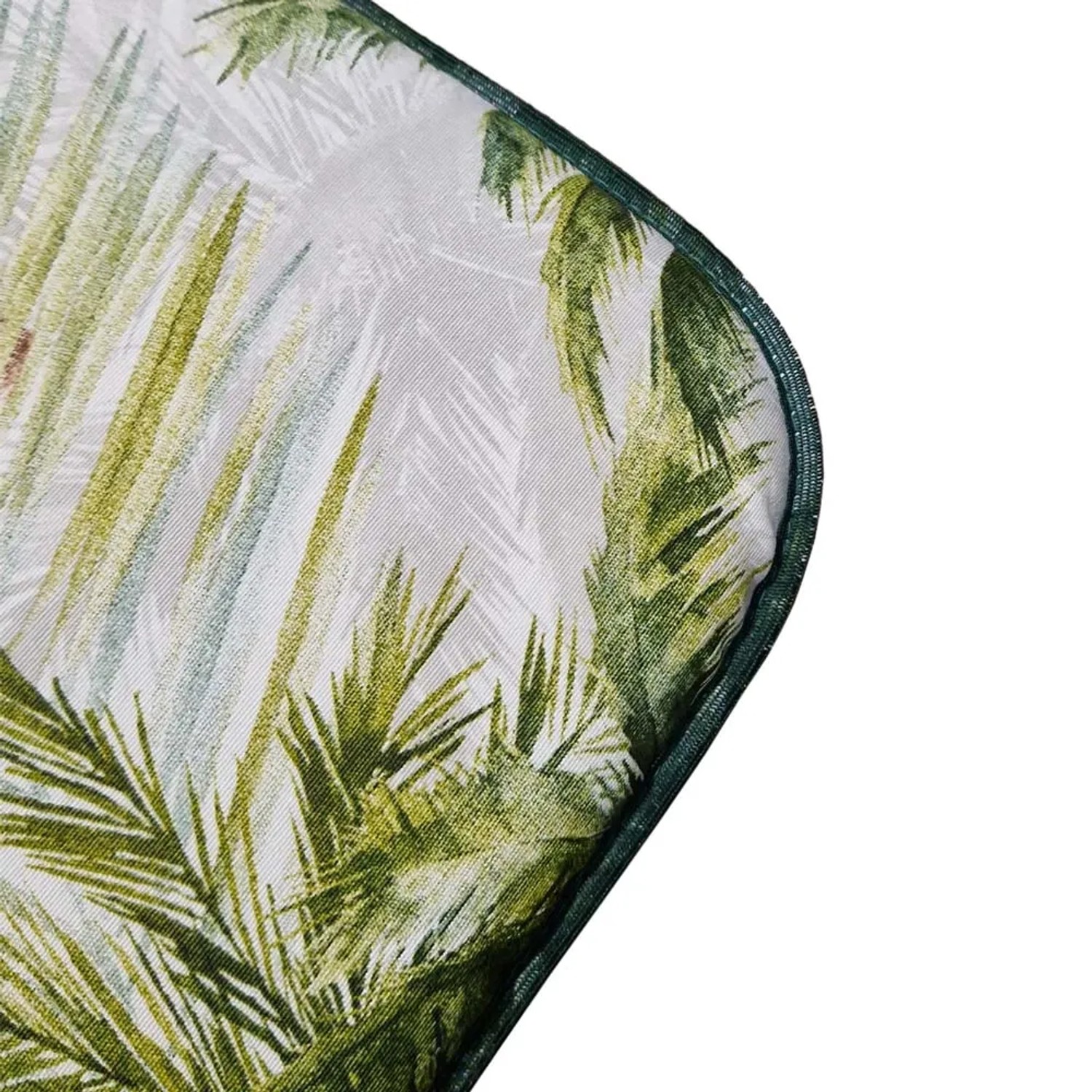 Dettaglio di un cuscino da esterno con motivo a foglie tropicali e bordo verde.