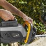 Tagliasiepi a batteria t.b.t. in azione, corpo grigio, manico giallo e batteria inserita.